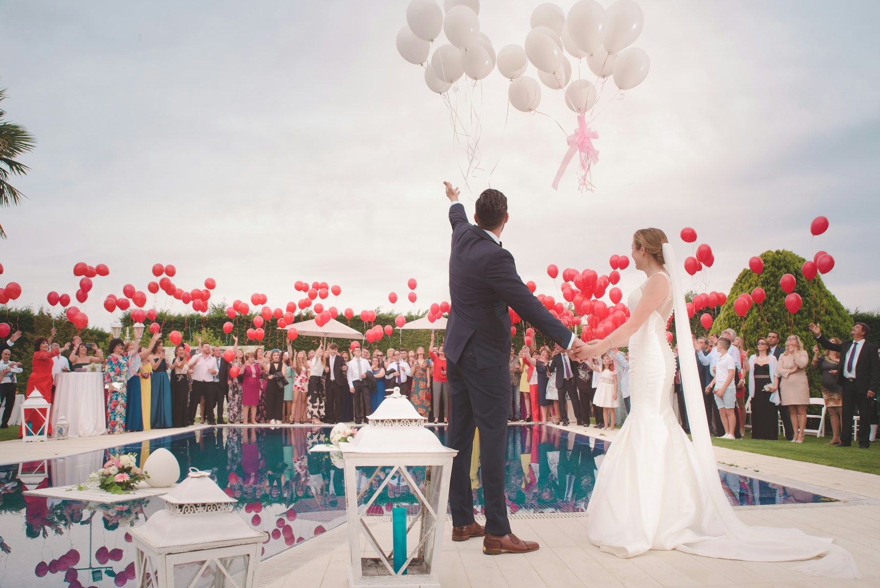 Newlyweds celebrating with their guests beneath a sky of balloons